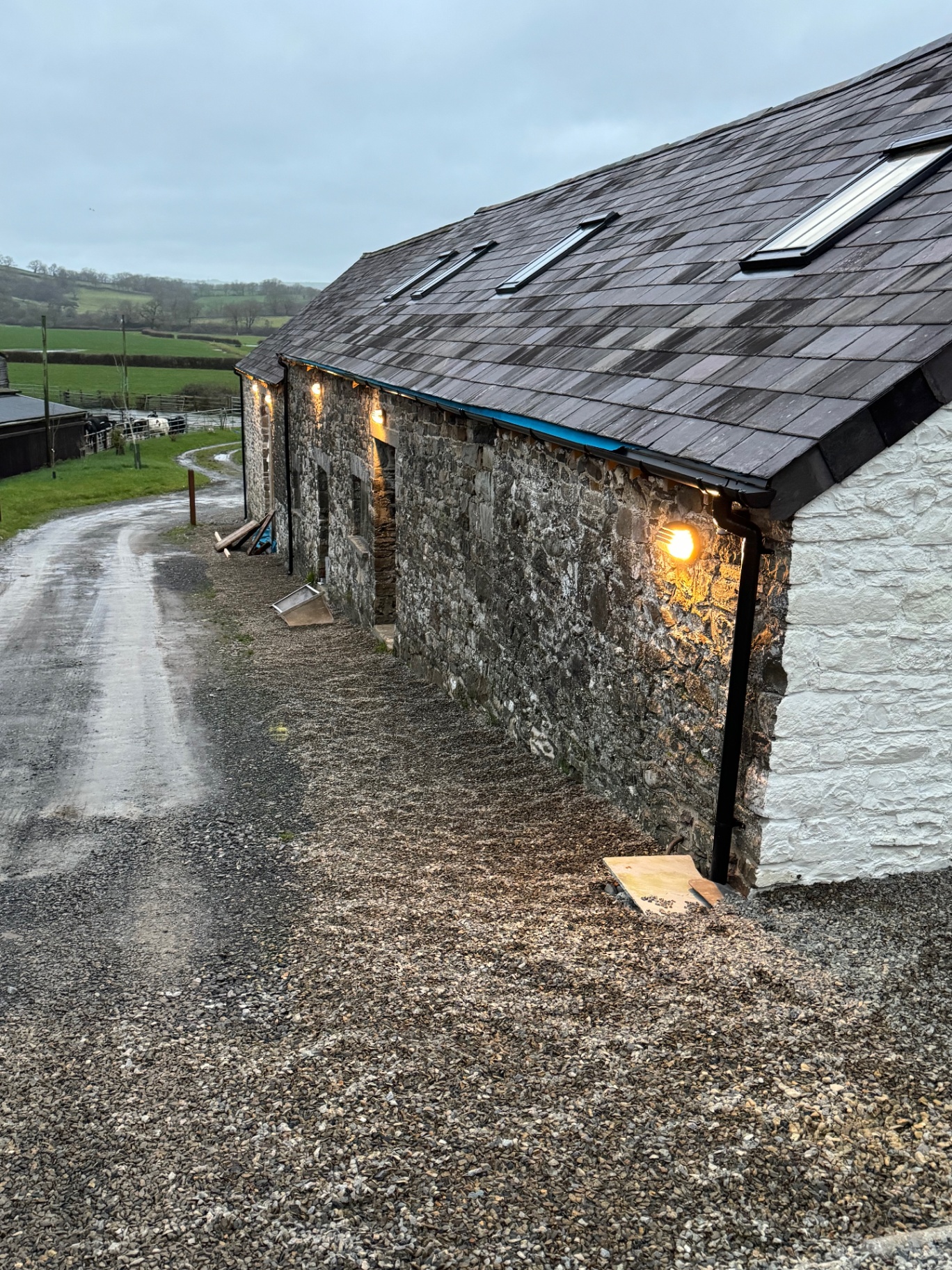 Stone farmhouse exterior with wall lights at dusk